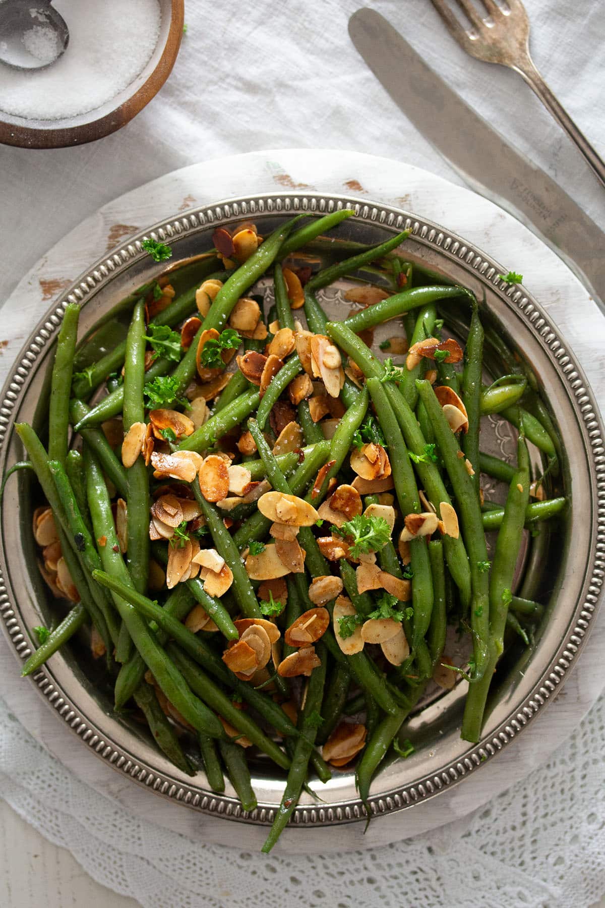 french green beans with roasted almonds on a silver platter.